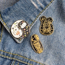 Detailed view of Ghibli-themed enamel pins on a blue denim jacket collar
