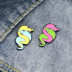 Close-up of colorful worm on a string enamel pins on dark blue denim fabric background