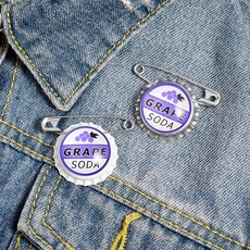 Detailed view of purple Grape Soda enamel bottle cap pins on blue denim jacket collar