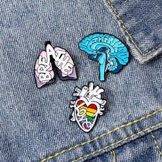 Detailed close-up of colorful enamel pins featuring brain heart and lung on denim fabric