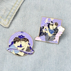 Close-up of enamel pins with purple illustration art on blue denim fabric texture
