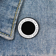 Macro shot of a round enamel duck pin on denim jacket featuring official bureau text