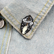 Detailed view of Lumos enamel pin featuring a magic wand on a denim jacket