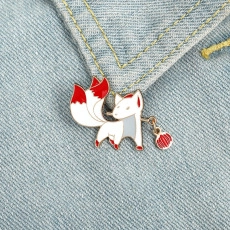 Detail of creative nine-tailed fox enamel brooch with red pendant on denim jacket fabric