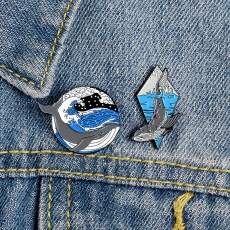 Detailed view of whale enamel pins set on a blue denim jacket pocket for accessory styling