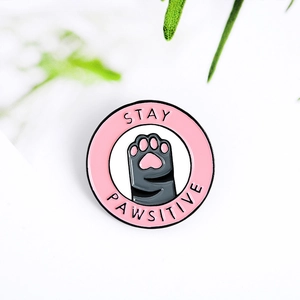 Detail of Stay Pawsitive pink cat paw enamel pin badge on a clean white background