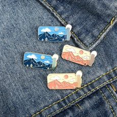 Detailed macro view of four landscape enamel pins on denim fabric with retro nature designs
