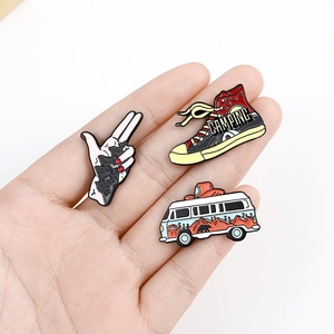 Close-up of enamel outdoor badges featuring mountain hand, camping shoe, and forest van