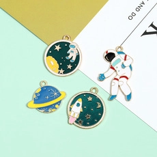 Detailed close-up of 4-piece astronaut and space planet enamel charms for DIY jewelry making