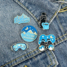 Detail of 5-piece outdoor hiking enamel pins set displayed on blue denim fabric background