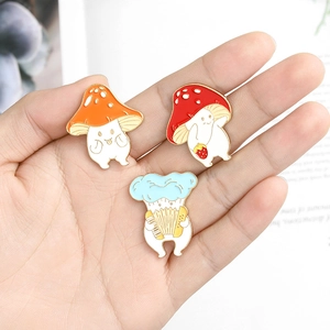 Cute enamel mushroom pins featuring violin and strawberry designs on palm of hand