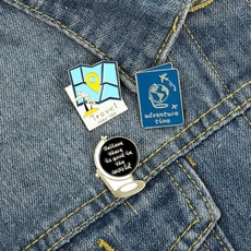 Travel-themed enamel pins featuring maps and globes pinned on blue denim fabric