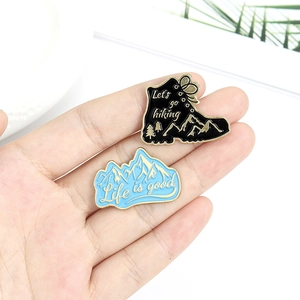 Outdoor hiking boot and mountain enamel pins with adventure themed gold lettering