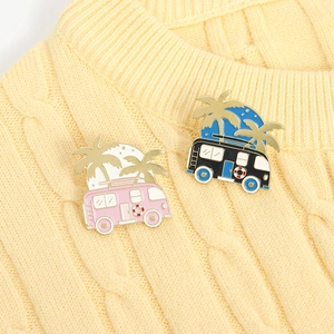 Detail of vintage camper bus enamel pins with coconut trees on yellow knit background