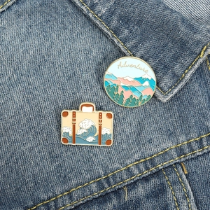Adventure enamel pin set with mountain landscape and wave pattern on denim jacket