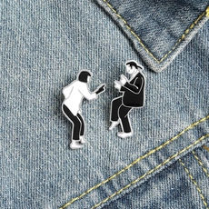 Detail of Pulp Fiction silhouette enamel pins on blue denim fabric in close-up view