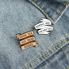 Close-up of enamel pins on denim jacket featuring reading and brain slogans