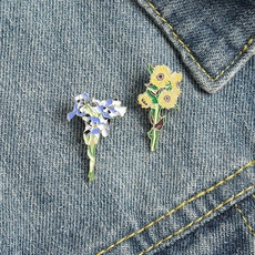 Detail of floral enamel pins inspired by Van Gogh art pinned on blue denim fabric