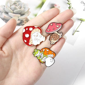 Three cute cartoon enamel pins featuring a cat, hedgehog, and frog with mushrooms