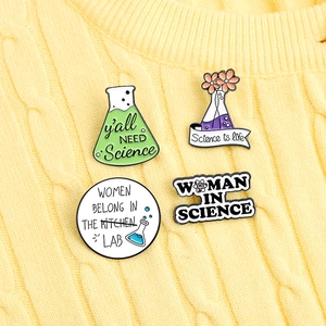 Close-up of four enamel pins with women in science themes on a yellow knitted background