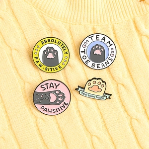 Set of four cute cartoon cat paw enamel pins featuring fun puns on a yellow knit sweater