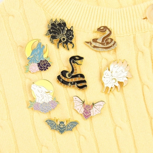 Detailed close-up of mythological animal enamel pins on a yellow knit sweater fabric