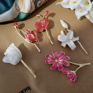 Detailed view of floral enamel brooches featuring tulips and lilies with gold metal accents