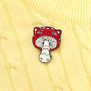 Creative red mushroom cat enamel pin pinned on a light yellow textured knit sweater