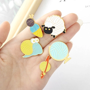 Set of five creative knitting-themed enamel pins featuring a snail, sheep, and yarn planet