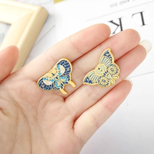 Detailed macro view of two blue enamel butterfly brooches held in hand for size display
