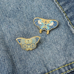 Detail of vintage butterfly enamel brooches with celestial moon and star patterns