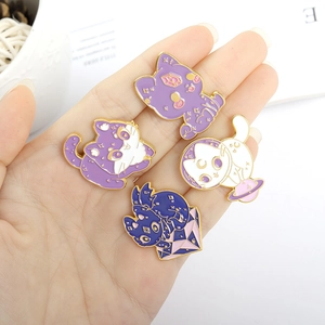 Set of four wizard cat enamel pins in purple galaxy themes held in hand for scale