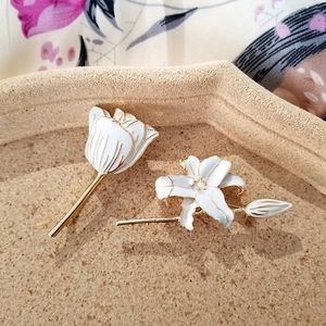 Detailed view of lily and tulip pins with white enamel finish and gold-toned plating