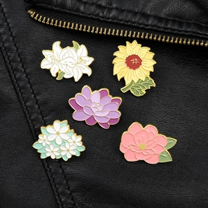 Exquisite floral enamel pins featuring lilies and sunflowers on a black leather background