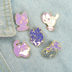 Detailed close-up of five cartoon cat enamel pins arranged on denim fabric background