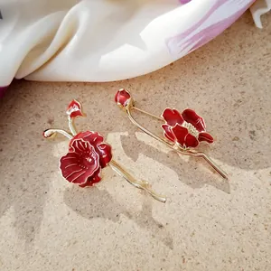 Close-up of elegant red poppy enamel brooches with gold finish on a silk scarf