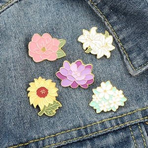 Five-piece sunflower and lily enamel pins set displayed on blue denim jacket