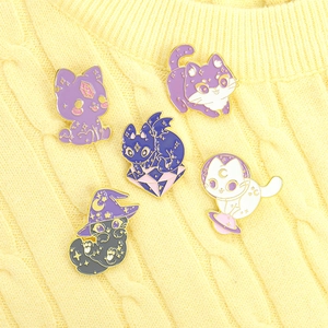 Detailed view of 5-piece cartoon cat and wizard enamel pins on yellow knitted sweater