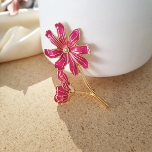 Detailed macro view of pink floral brooch with gold stems and enamel lily petals