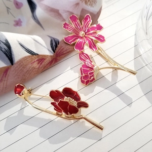 Detail of floral enamel brooches with intricate golden textures and vibrant pink petals