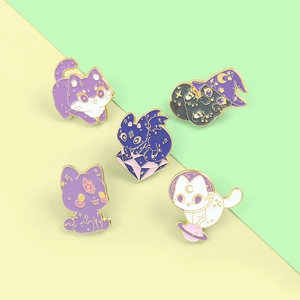 Detail view of five cartoon enamel cat pins with wizard and cosmic moon designs