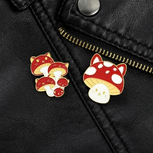 Detail of red mushroom enamel pins with cat face patterns on a black leather jacket