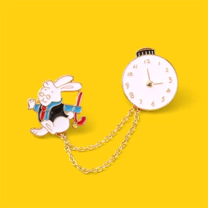 Detail of a rabbit and clock enamel brooch with golden chain link on a yellow base