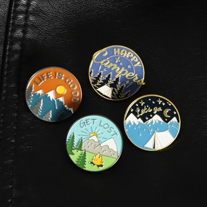 Set of four colorful enamel outdoor camping pins on textured black leather backdrop
