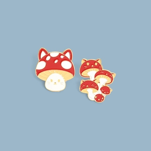 Detailed close-up of creative red mushroom enamel pins with cat ears on golden metal