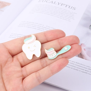 Cute tooth and toothbrush enamel pins set held in hand for dental care theme accessories