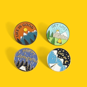 Set of four circular outdoor camping enamel pins with mountain and bonfire motifs