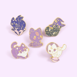 Macro view of five assorted wizard and space-themed cat enamel pins with gold plating