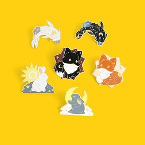 Detail of colorful enamel animal brooches with fox, rabbit, and koi fish designs on yellow