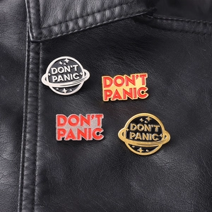 Detail of four Don't Panic enamel planet pins pinned on a black leather jacket